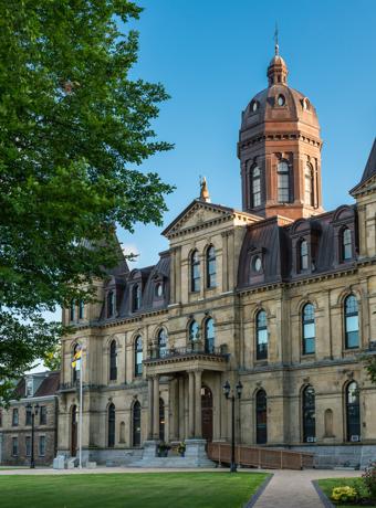 Historic Fredericton Legislative Building with its grand Victorian architecture and lush surrounding greenery.