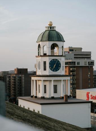 he clock tower of Halifax Town Hall with its classical architecture and prominent clock face, against a twilight sky.