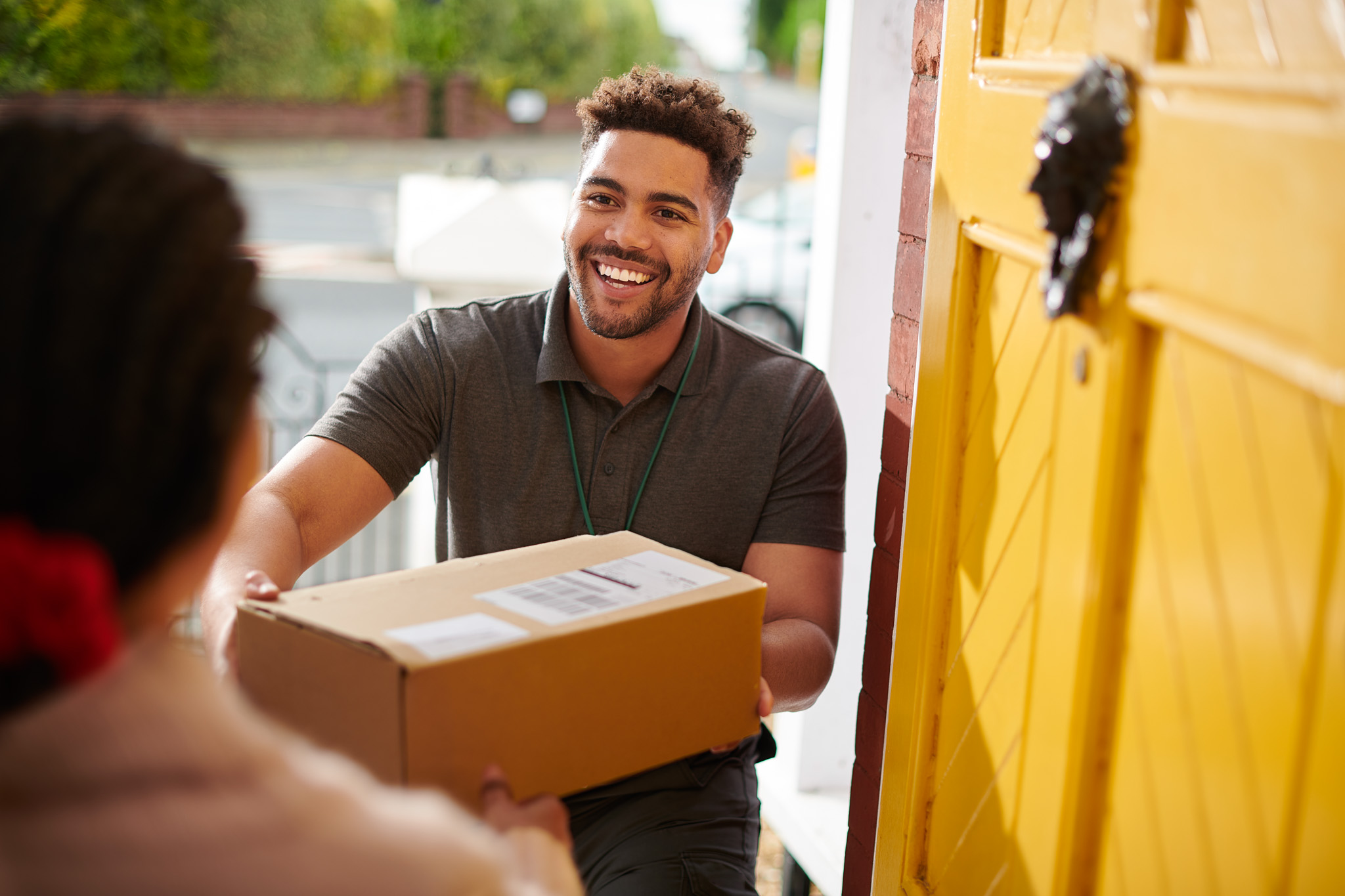 Alt Text: Friendly Canadian Preferred Moving delivery personnel handing over a package to a customer at their doorstep.