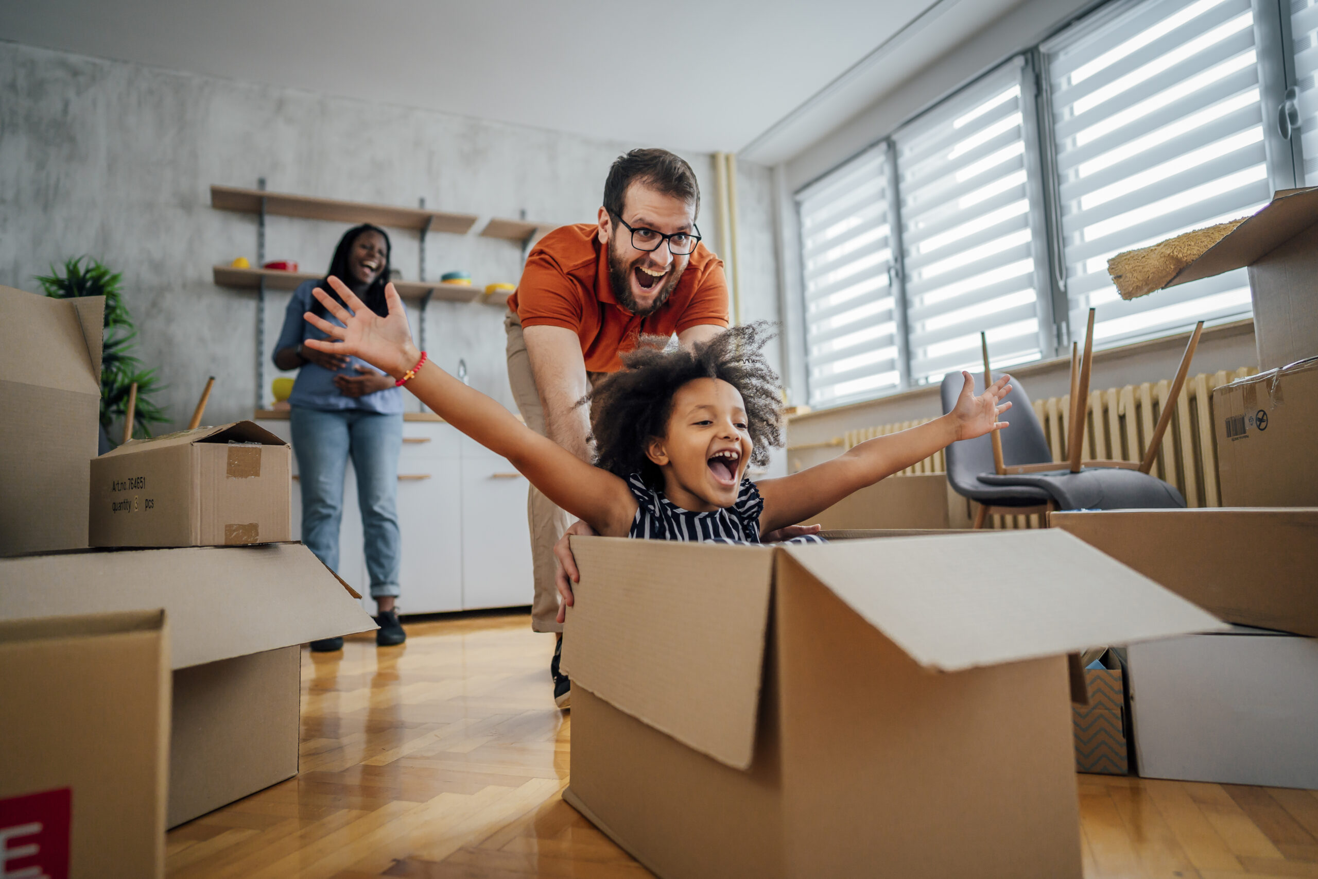 A happy family enjoying their new home among boxes marked with Canadian Preferred Moving.