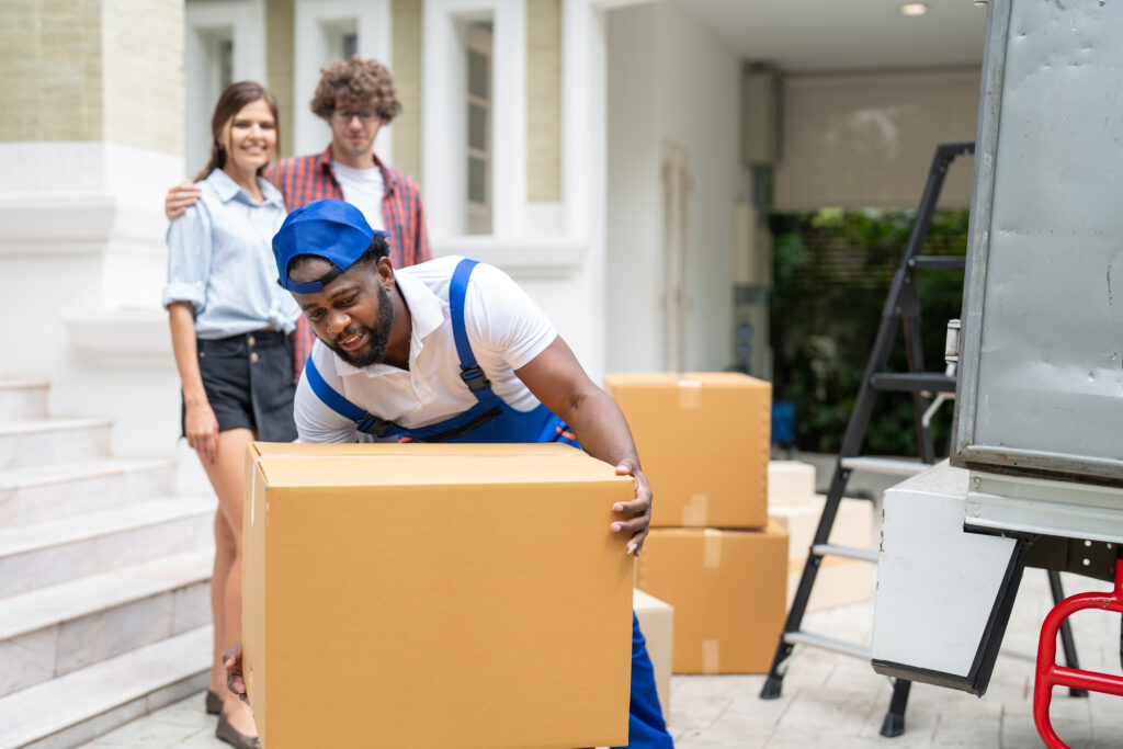 CPM mover worker in blue uniform unloading cardboard boxes from truck. Professional delivery and moving service.