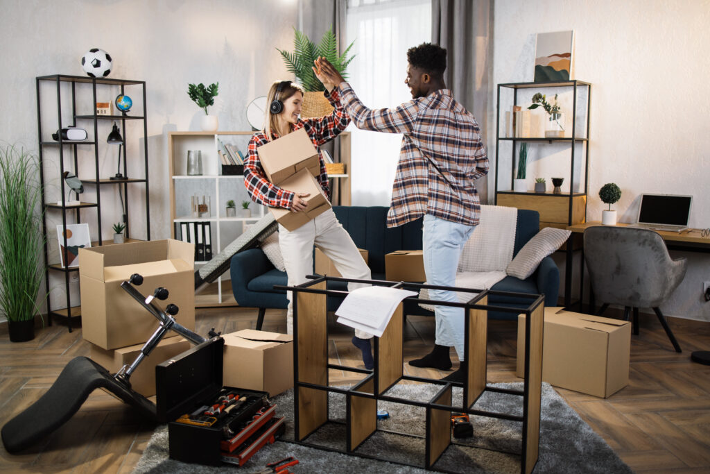 Cheerful woman giving high five to her boyfriend while holding carton boxes