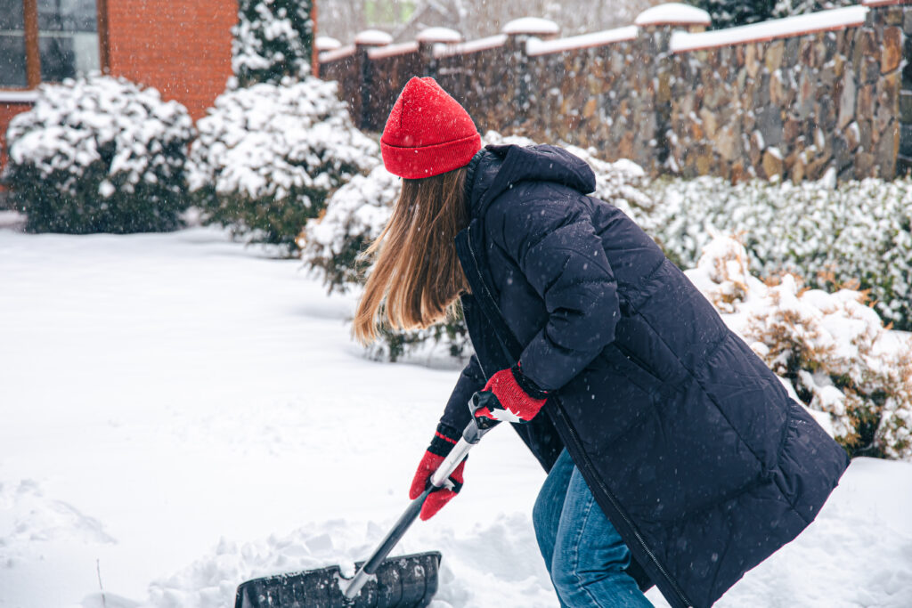 Canadian young woman cleans snow in snowy weather.